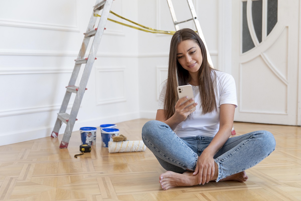 Mulher em reforma do seu apartamento com celular na mão